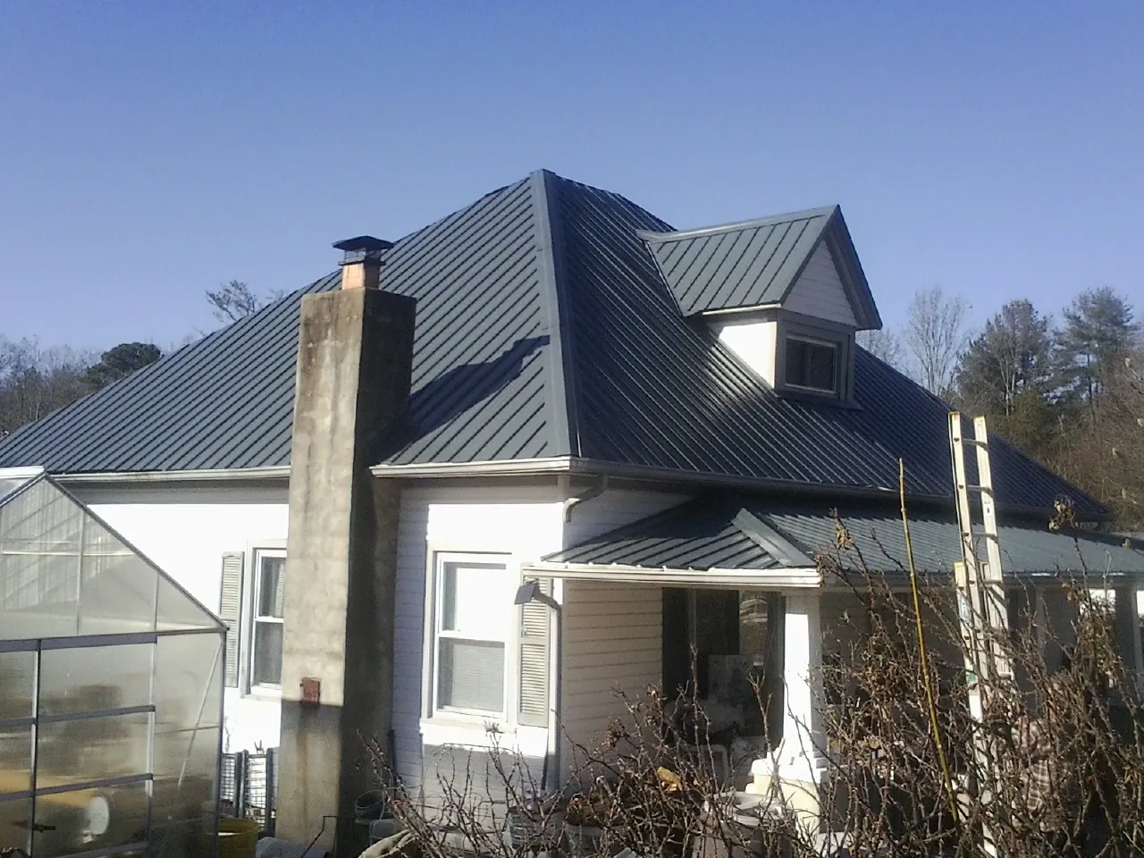 Dark blue standing seam metal roof on a white farmhouse with dormer — Slate & Tile Roof Repair by Roofing Brothers in Canaan
